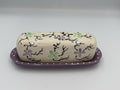 Cream ceramic butter dish lid painted with lavender and green flowers on a lavender polka-dot tray