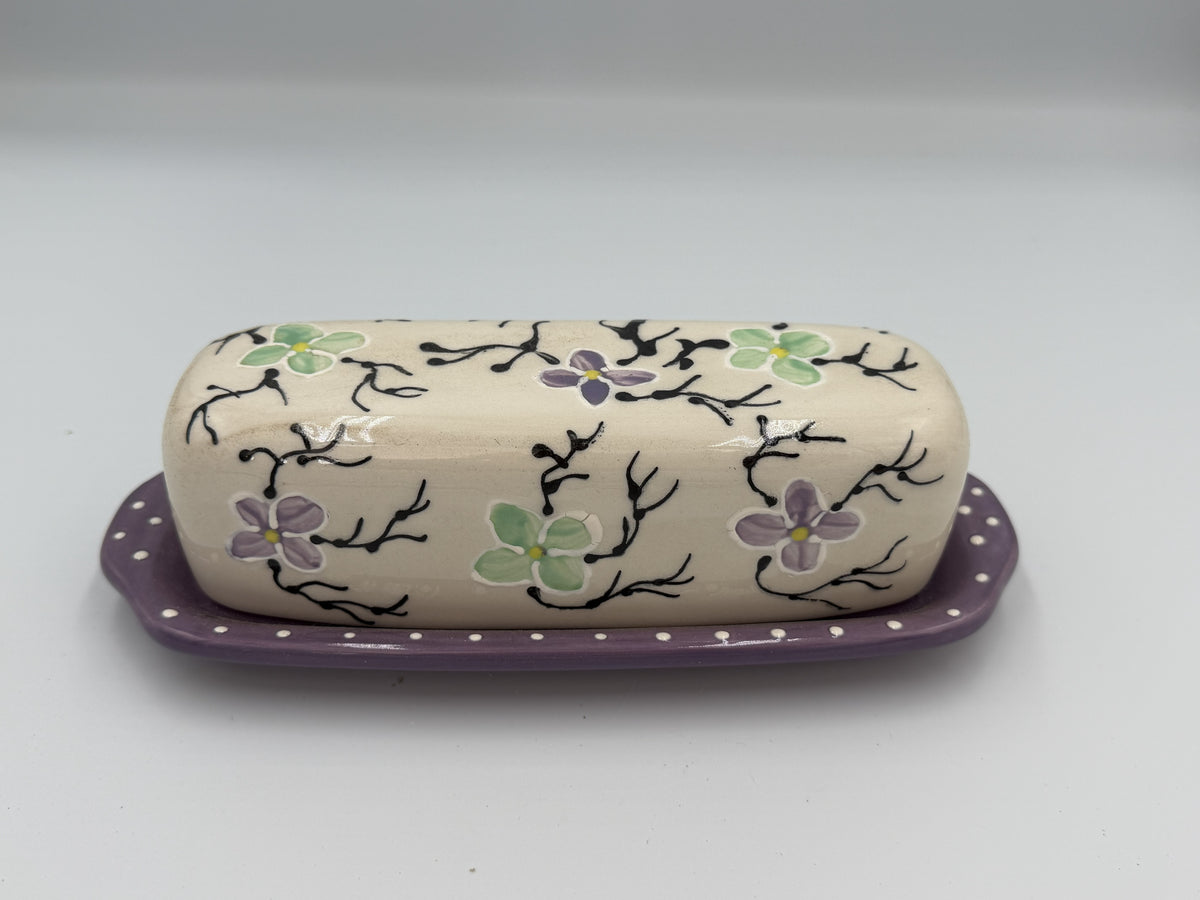 Cream ceramic butter dish lid painted with lavender and green flowers on a lavender polka-dot tray