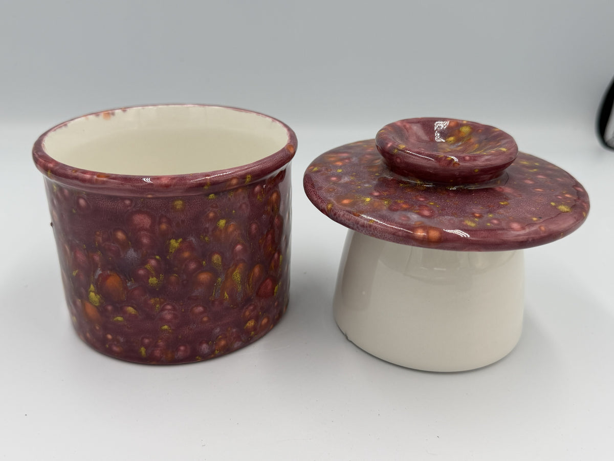 Maroon speckled ceramic butter bell base and bell-shaped lid side by side