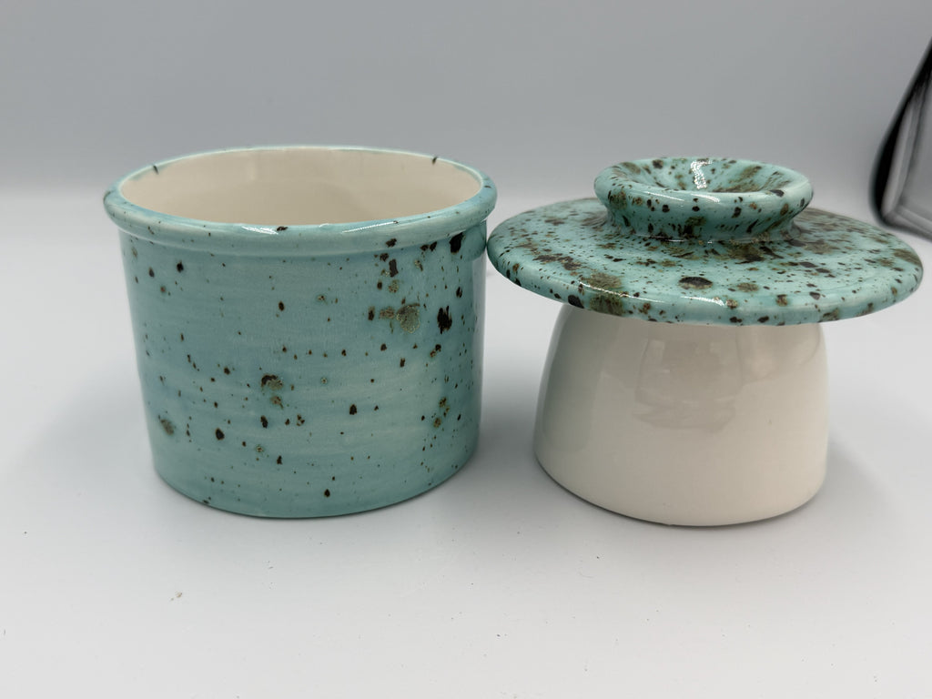 Turquoise speckled ceramic butter bell base and bell-shaped lid side by side
