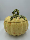 Yellow speckled ceramic harvest pumpkin with green leafy lid and curly stem