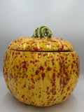 Large golden yellow ceramic pumpkin jar with red, orange, and green speckles and green stem lid
