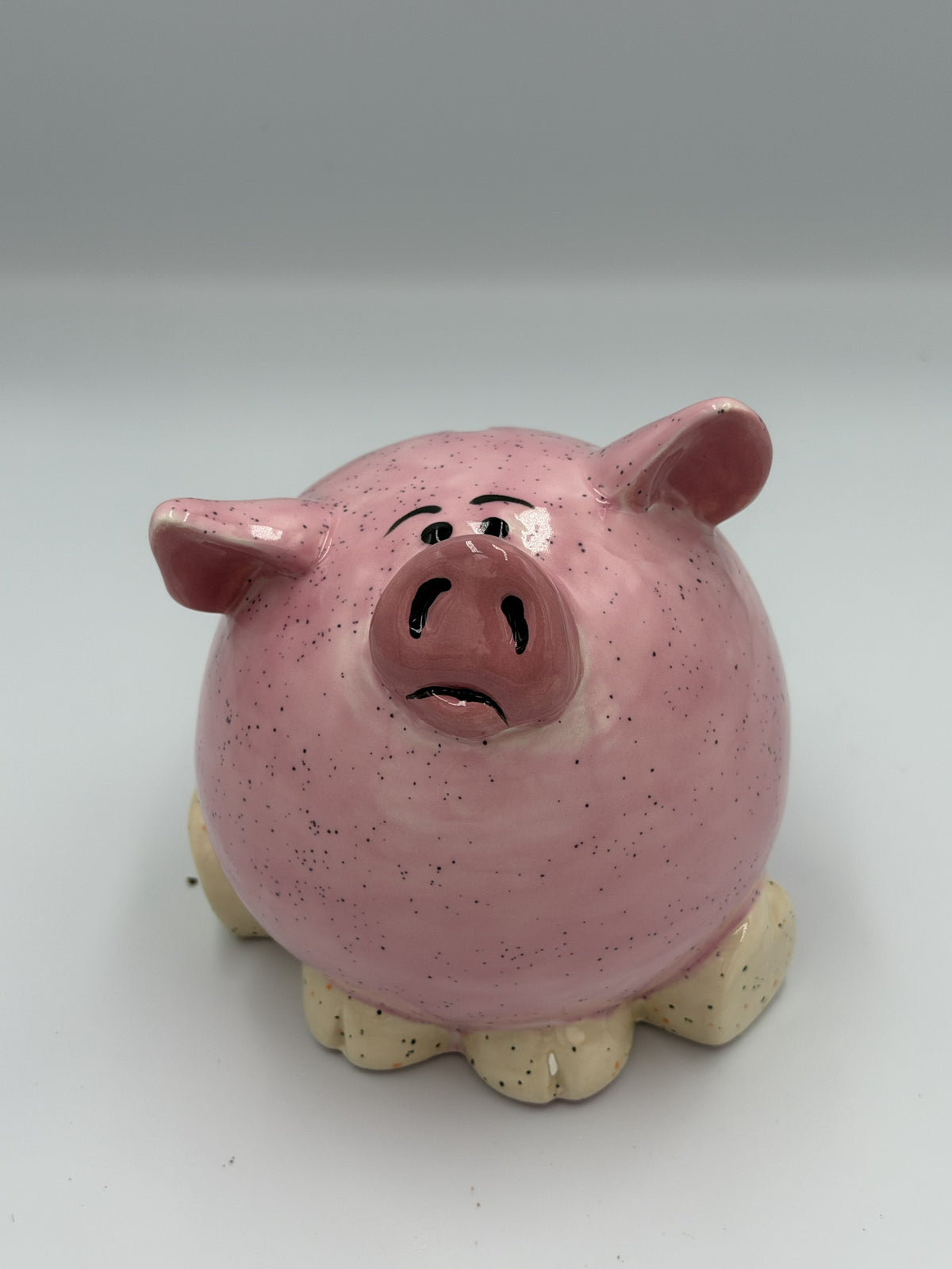 Round dark pink speckled ceramic pig bank with glossy snout, pink ears, and cream hooves