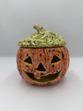 Coral-orange speckled ceramic jack-o'-lantern with green textured lid and stem