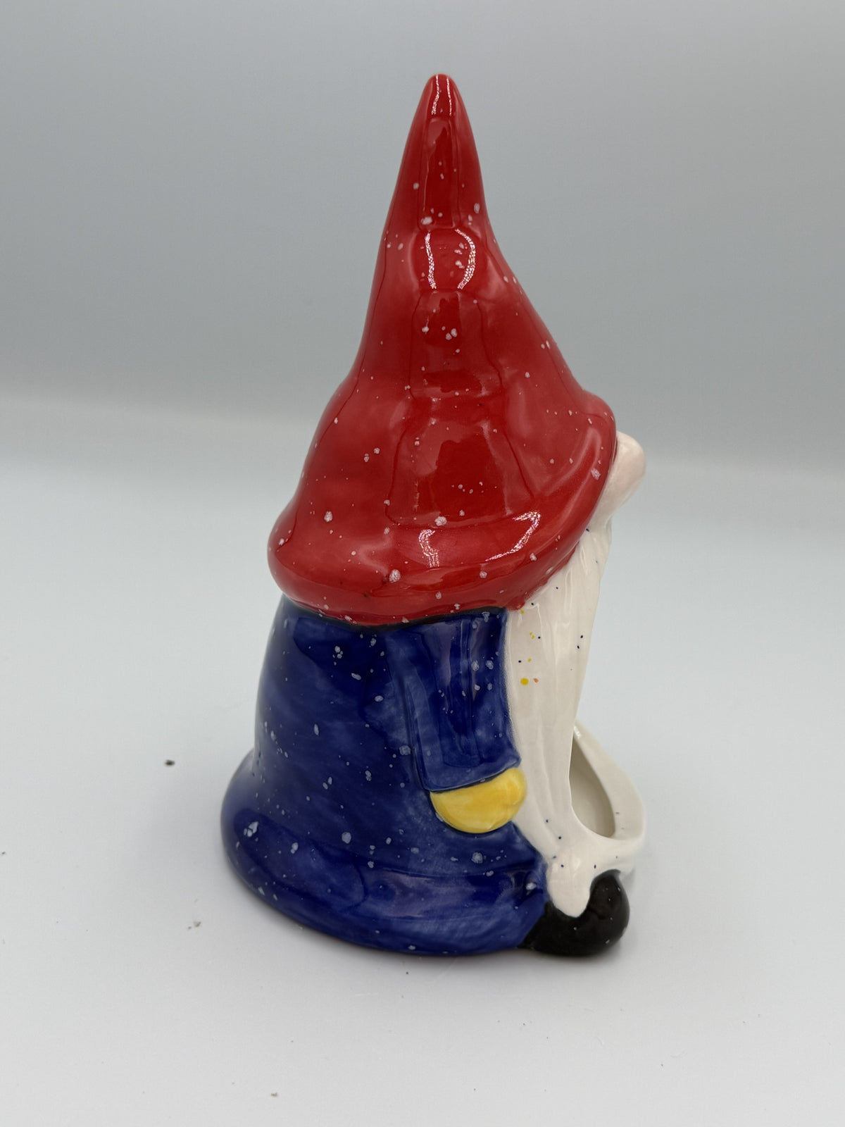 Side view of gnome scrubby holder with red speckled hat, navy coat, and yellow mitten