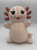 Large blush pink ceramic axolotl bank sitting upright with polka-dot gills and blue eyes