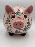 Front view of large pink speckled ceramic pig bank hand-painted with teal flowers and blue eyes