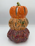 Stacked ceramic pumpkin lantern in orange, peach, and plum with leaf-shaped cutouts