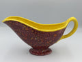 Maroon speckled ceramic gravy boat with yellow rim and handle