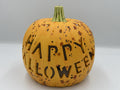 Orange speckled ceramic pumpkin with carved HAPPY HALLOWEEN lettering and green stem