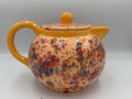 Large peach speckled ceramic teapot with marigold handle, spout, and flat lid