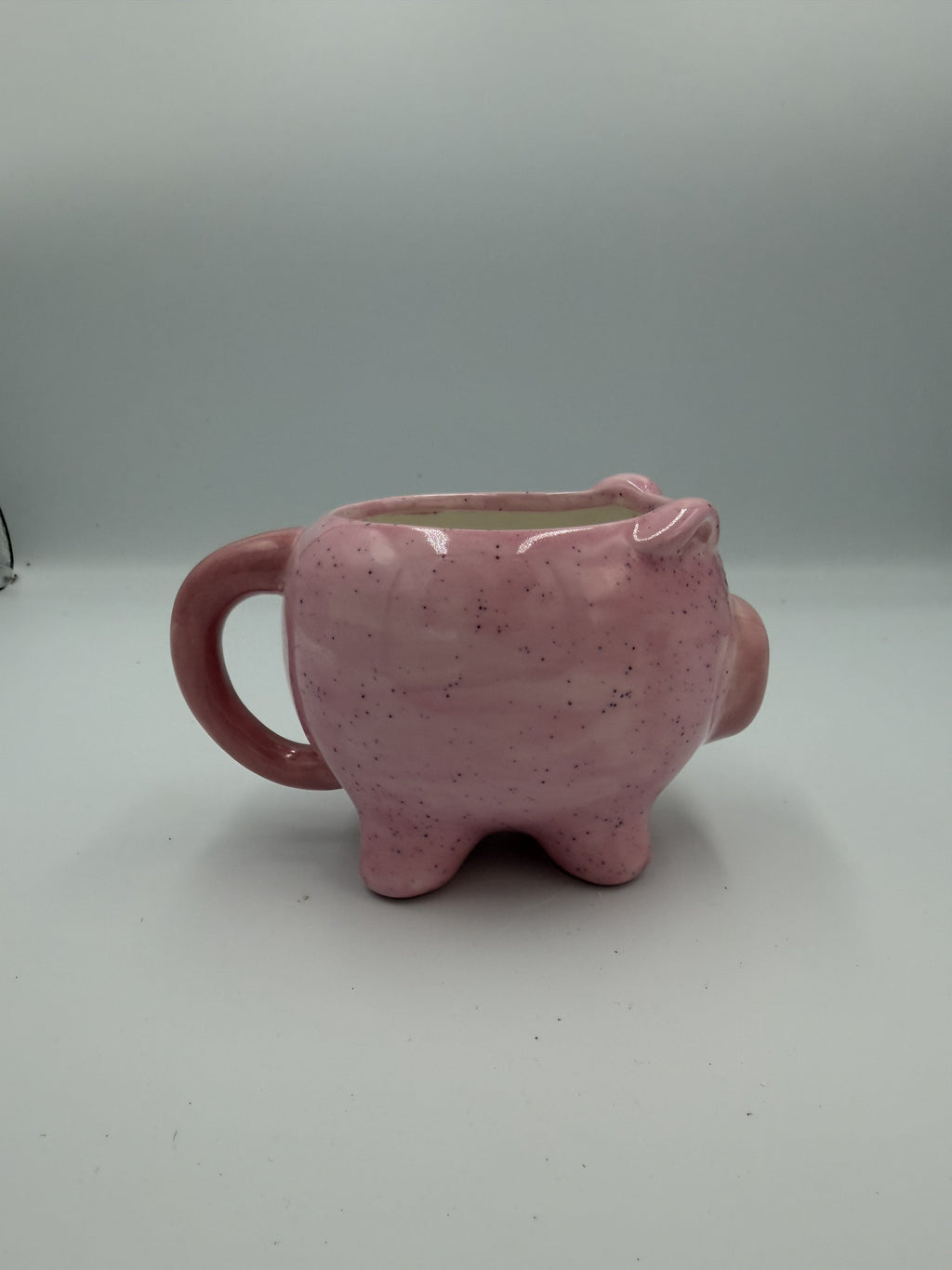 Front view of a glossy pink pig-shaped mug with painted eyes and snout