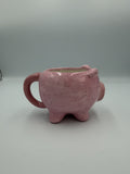 Front view of a glossy pink pig-shaped mug with painted eyes and snout
