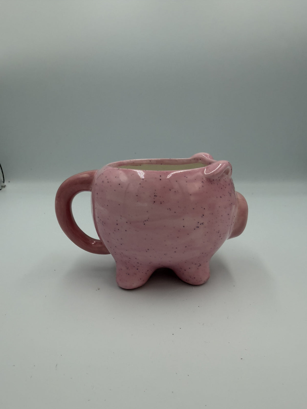 Front view of a glossy pink pig-shaped mug with painted eyes and snout
