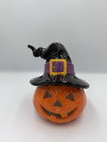 Orange ceramic jack-o'-lantern wearing a black witch hat with purple band and gold buckle